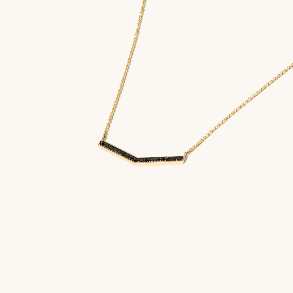 Angled view of Jewellers District's V-Shaped Gold Pendant Necklace with Black Spinels in 10k Yellow Gold