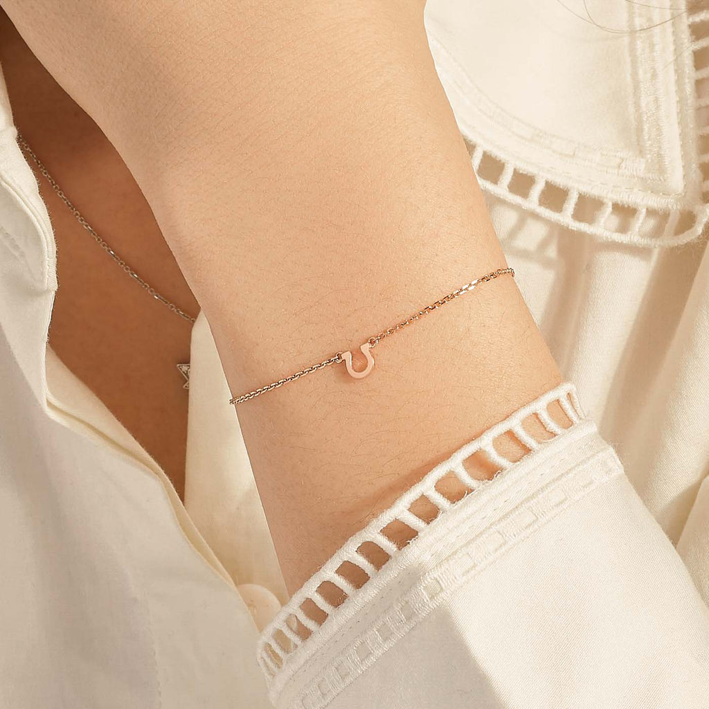 Model wearing Jewellers District's Petite Gold Horseshoe Charm Bracelet in 10k Rose Gold #2