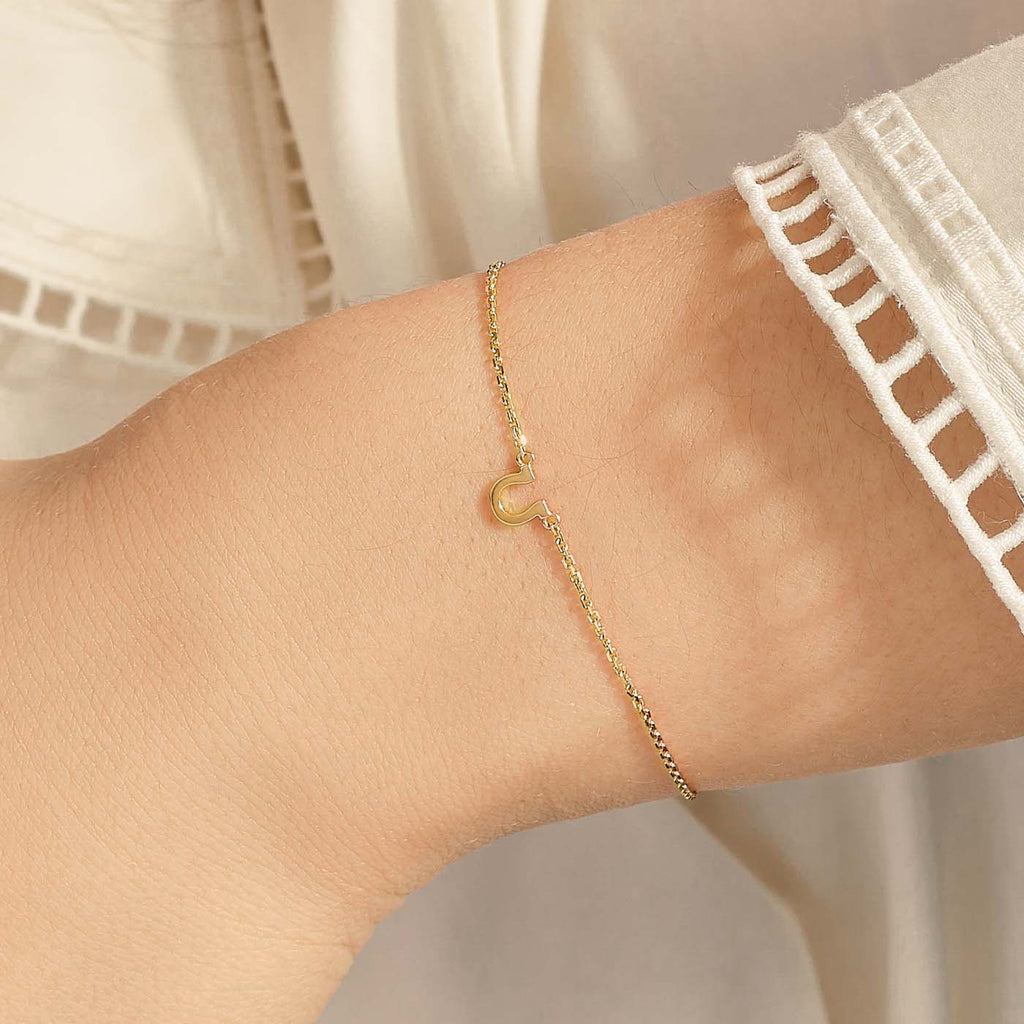 Model wearing Jewellers District's Petite Gold Horseshoe Charm Bracelet in 10k Yellow Gold