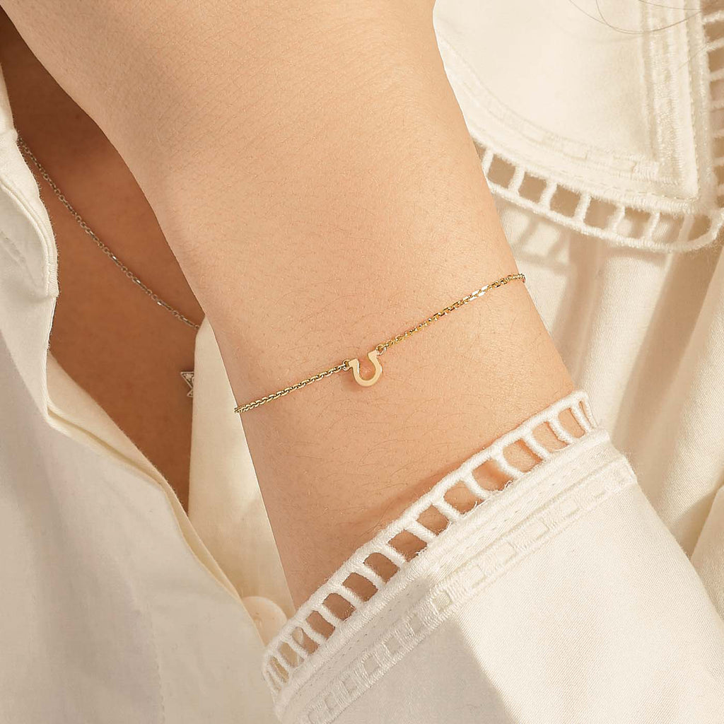 Model wearing Jewellers District's Petite Gold Horseshoe Charm Bracelet in 10k Yellow Gold #2