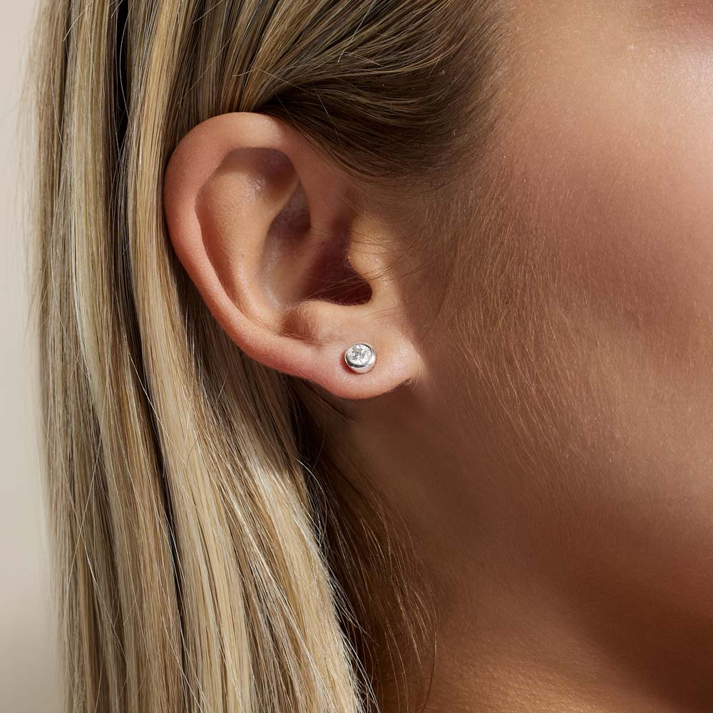 Model wearing Jewellers District's Bold Bezel-Set Round Cut Diamond Studs in 10k White Gold