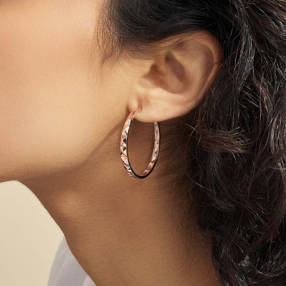 Model wearing Jewellers District's Faceted Gold Hoop Earrings in 10k Rose Gold