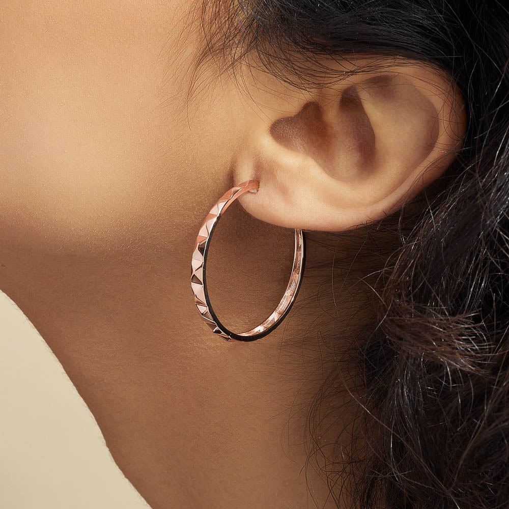 Model wearing Jewellers District's Faceted Gold Hoop Earrings in 10k Rose Gold #4