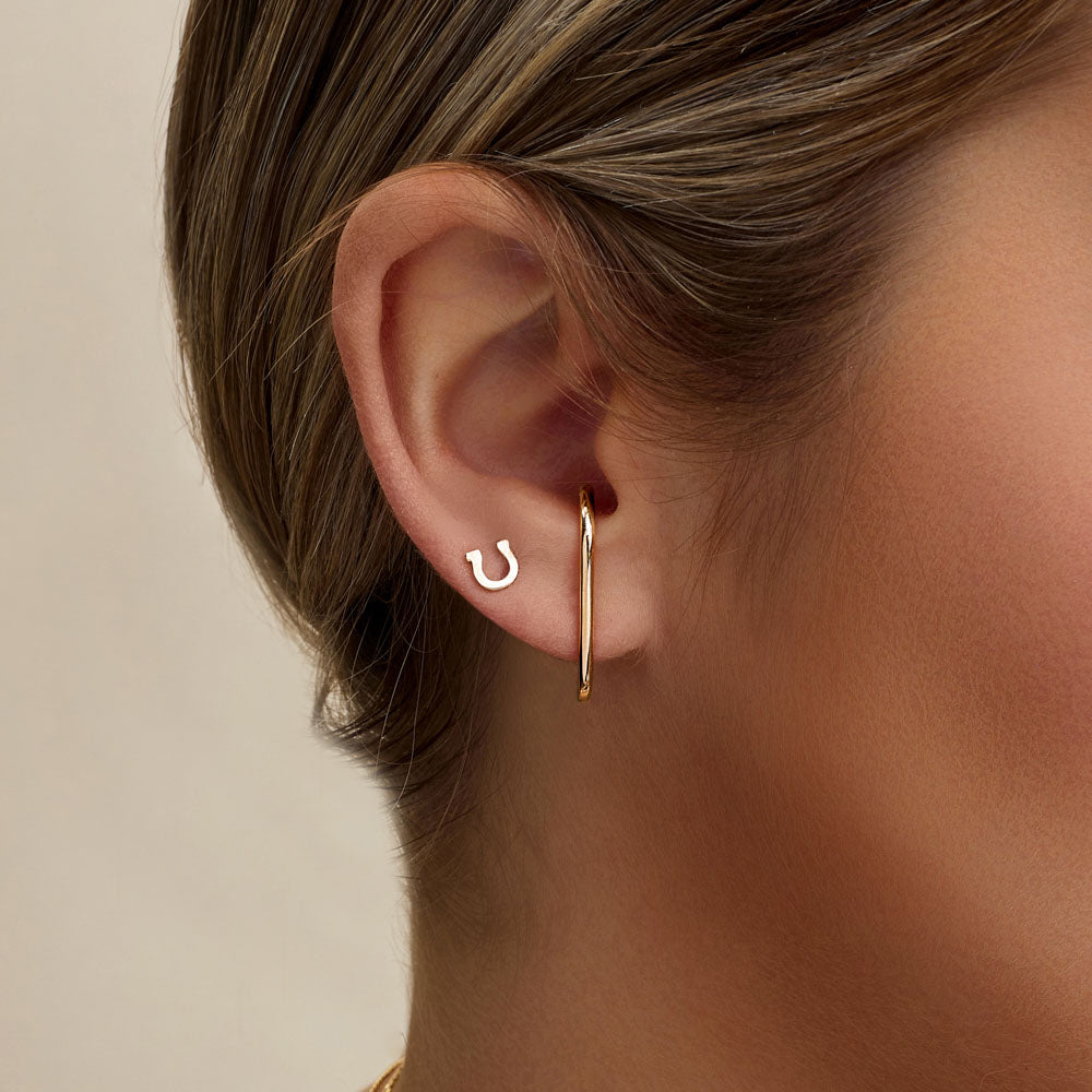 Model wearing Jewellers District's Gold Horseshoe Stud Earrings in 10k Yellow Gold #2