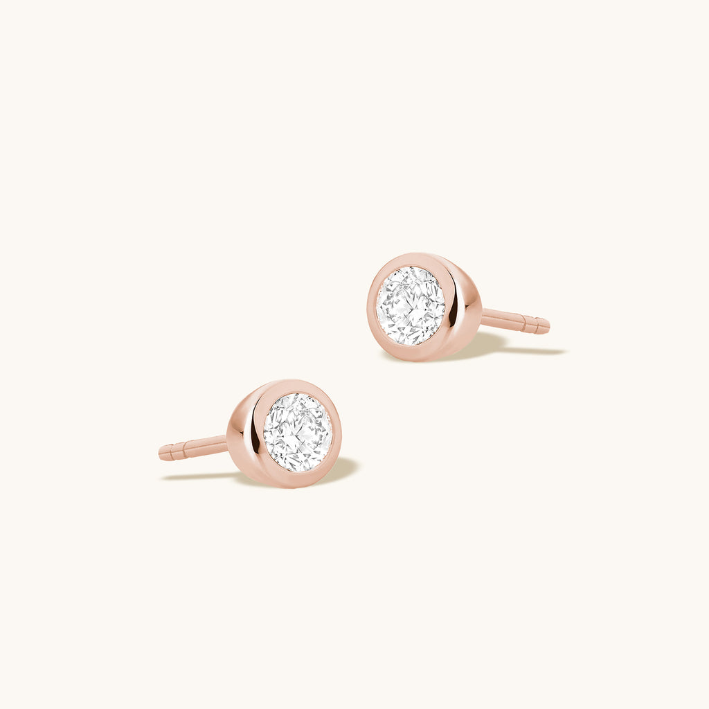 Angled view of Jewellers District's Bold Bezel-Set Round Cut Diamond Studs in 10k Rose Gold