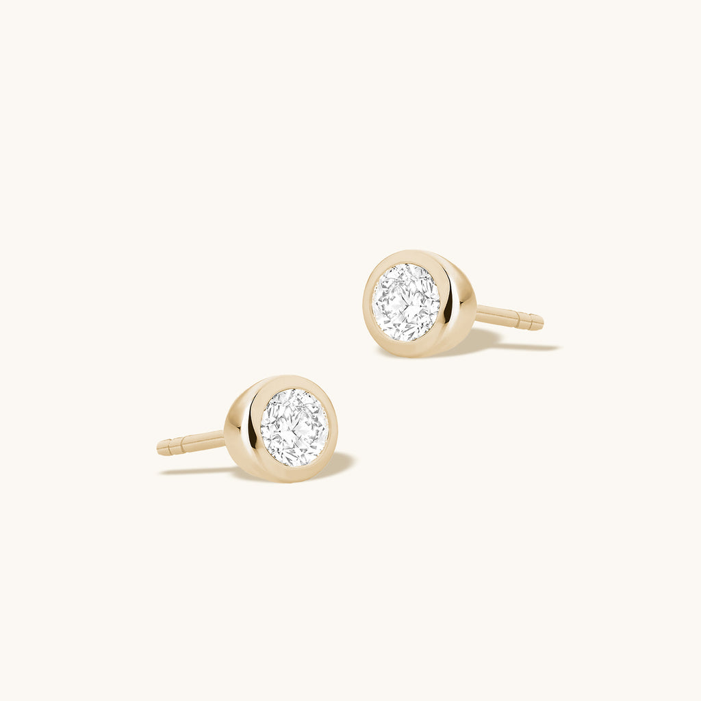 Angled view of Jewellers District's Bold Bezel-Set Round Cut Diamond Studs in 10k Yellow Gold