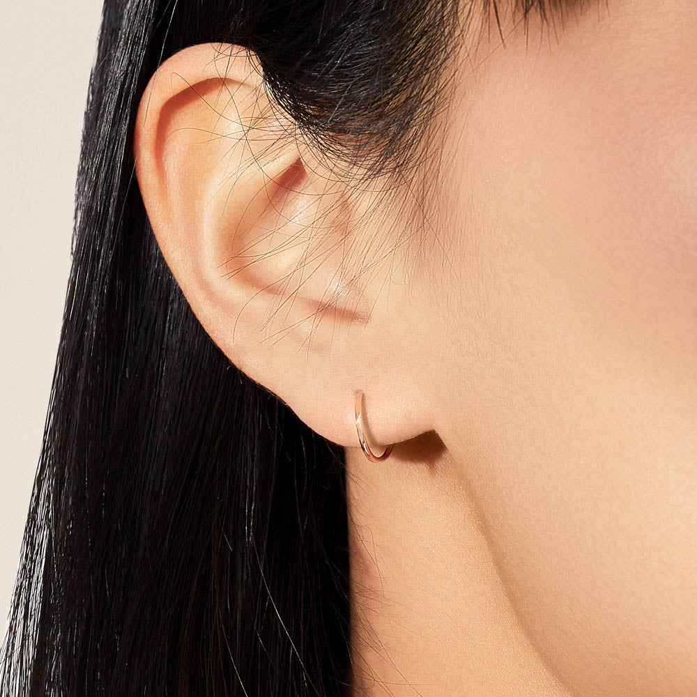 Model wearing Jewellers District's Petite Gold Hoop Earrings in 14k Rose Gold