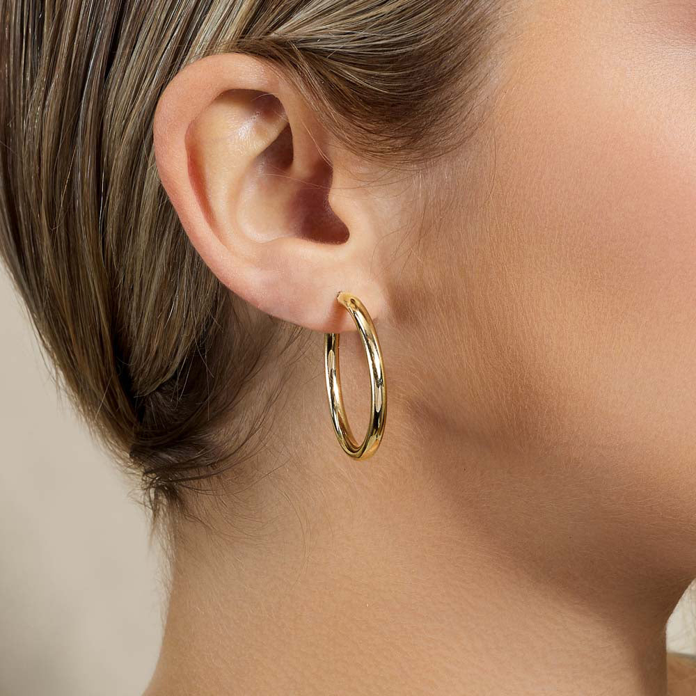 Model wearing Jewellers District's Gold Hoop Earrings in 10k Yellow Gold #3