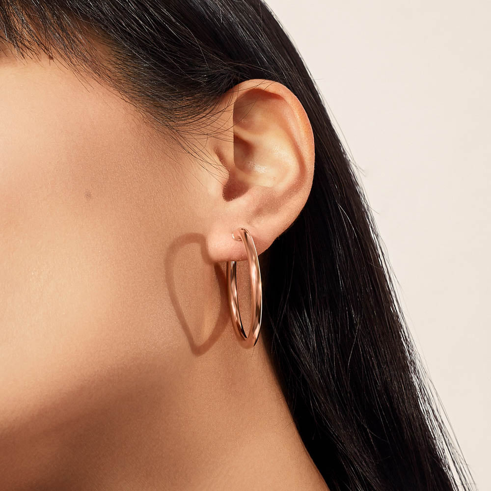 Model wearing Jewellers District's Thin Gold Hoop Earrings in 10k Rose Gold #2