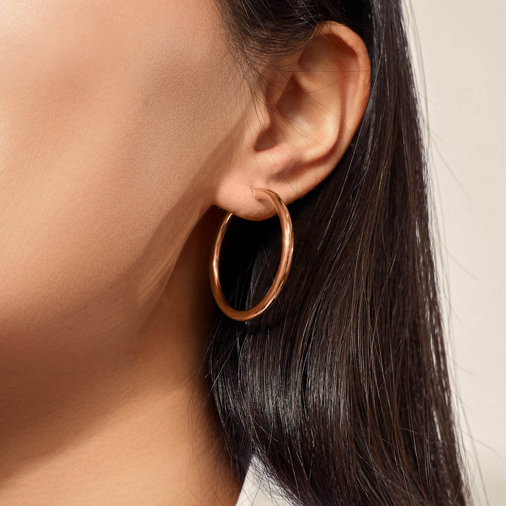 Model wearing Jewellers District's Thin Gold Hoop Earrings in 10k Rose Gold #3