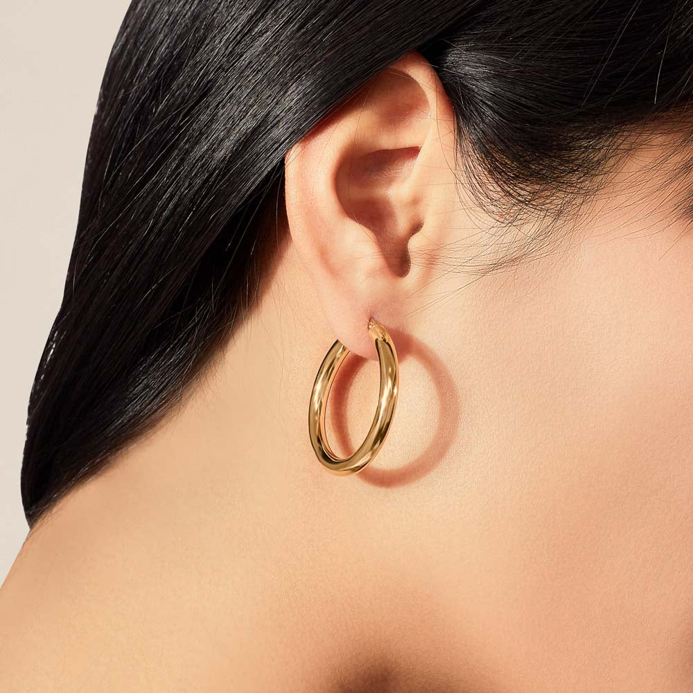 Model wearing Jewellers District's Thick Gold Hoop Earrings in 10k Yellow Gold #2