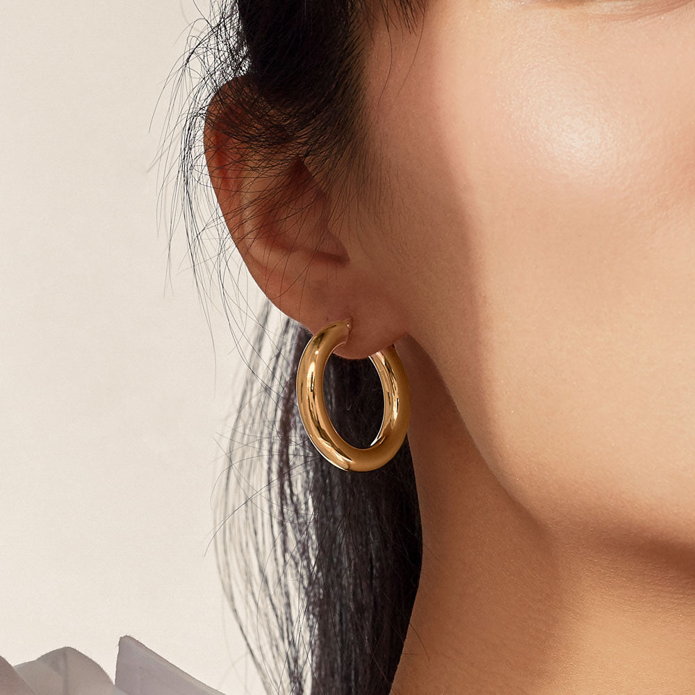 Model wearing Jewellers District's Bold Gold Hoop Earrings in 10k Yellow Gold