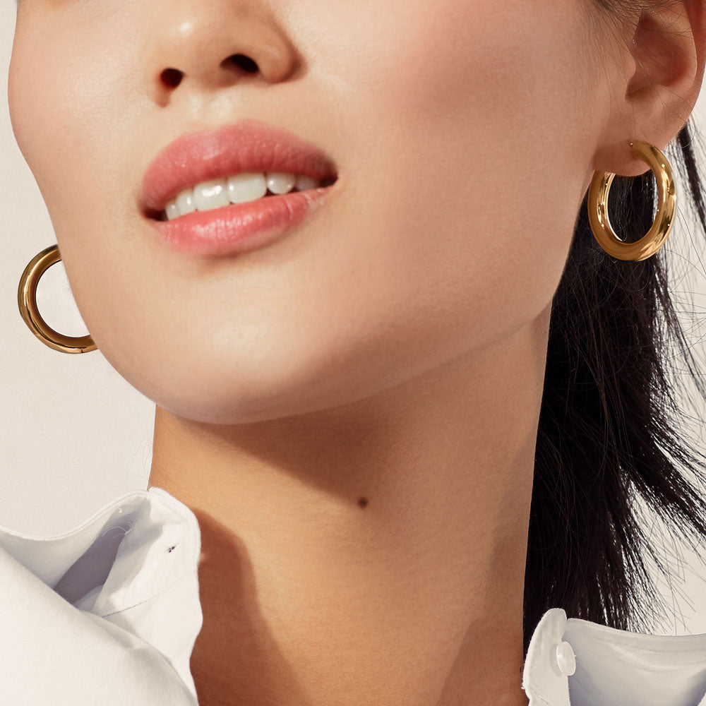 Model wearing Jewellers District's Bold Gold Hoop Earrings in 10k Yellow Gold #2