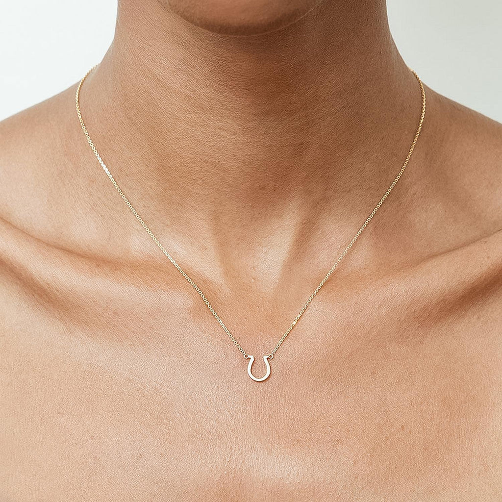 Model wearing Jewellers District's Gold Horseshoe Pendant Necklace in 14k Yellow Gold